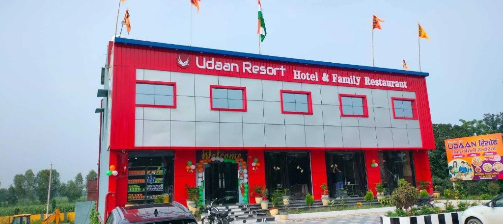 Udaan Resort in daylight, red and grey front with the name above the entrance