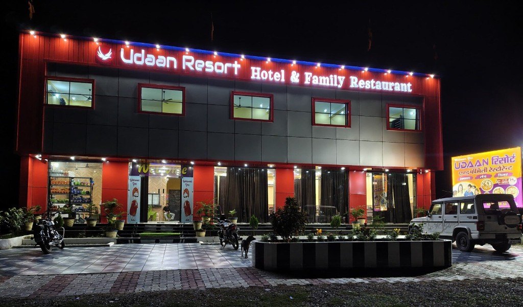 The front of Udaan Resort at night, with the lit sign above the entrance